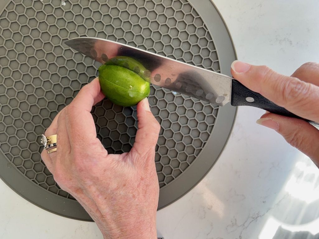 woman's hands holding a slitting a lime on a rubbery cutting mat
