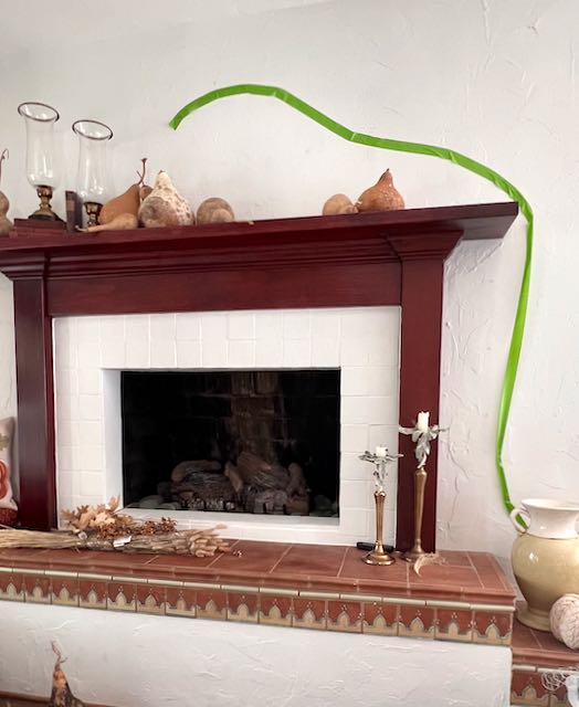 green painter's tape is on the wall above and beside a fireplace