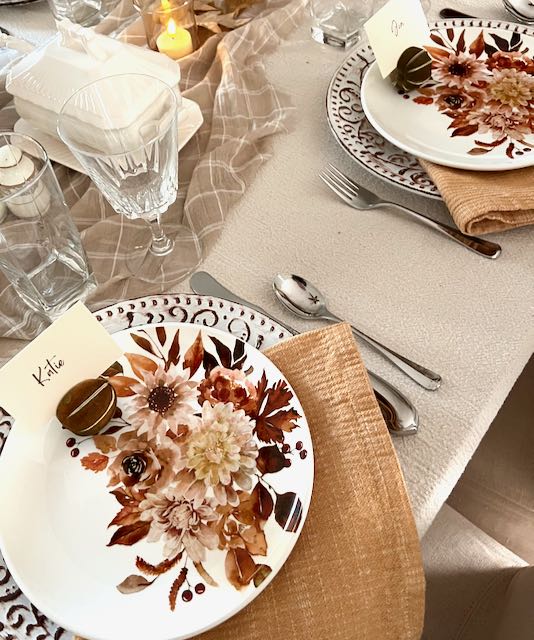 two placesettings with floral salad plates atop dinner plates and gold napkins