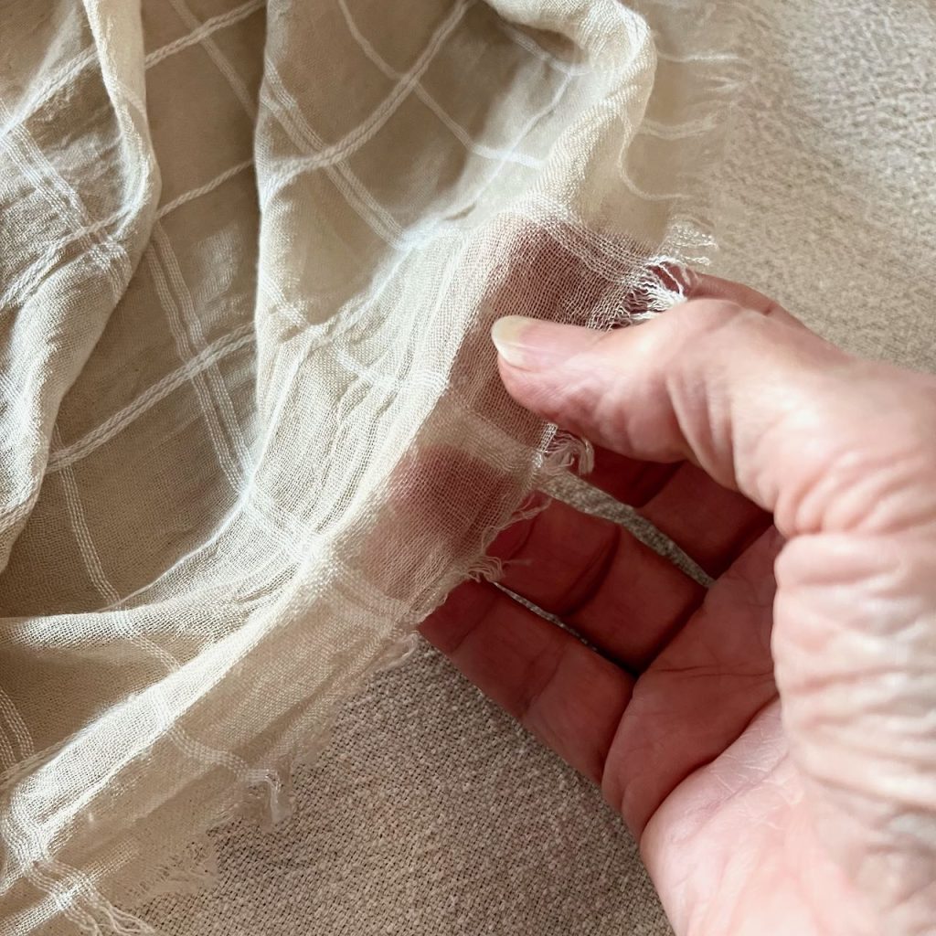 closeup of woman's hand fingering the thin shawl