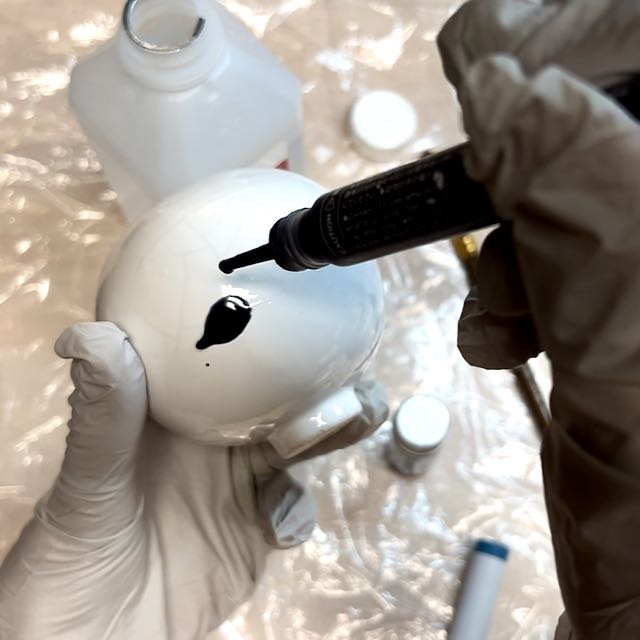 closeup of a dropper dispensing a drop of grey ink