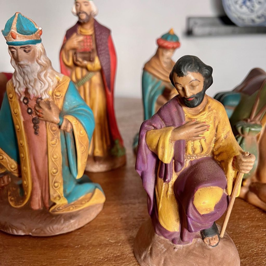 Dated, brightly colored nativity statues are on a wood table