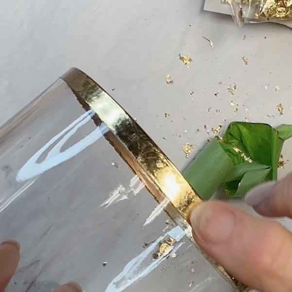 closeup of gold leaf sheets applied to the rim of a clear glass vase