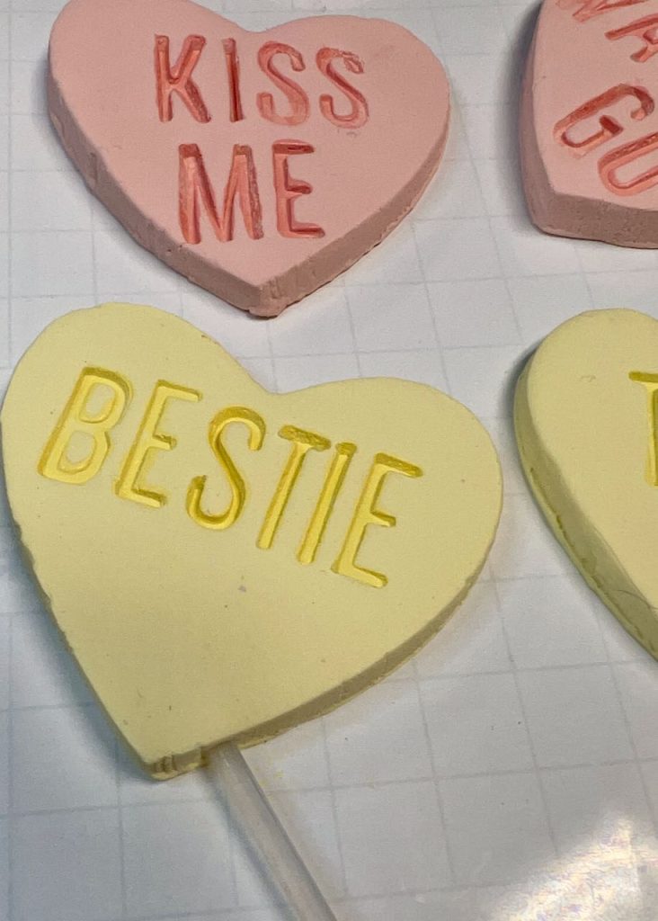 completed hearts with a hole tool making a hole at an angle in the "BESTIE" heart