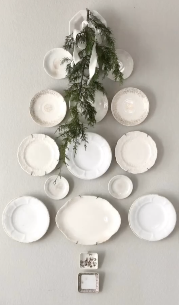 Vintage ironstone dishes and trays arranged on a wall in the shape of a Christmas tree