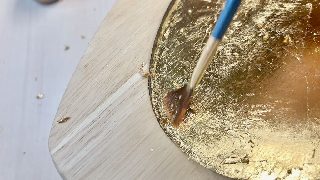 closeup of paintbrush sweeping off the extra fragments of gold leafing