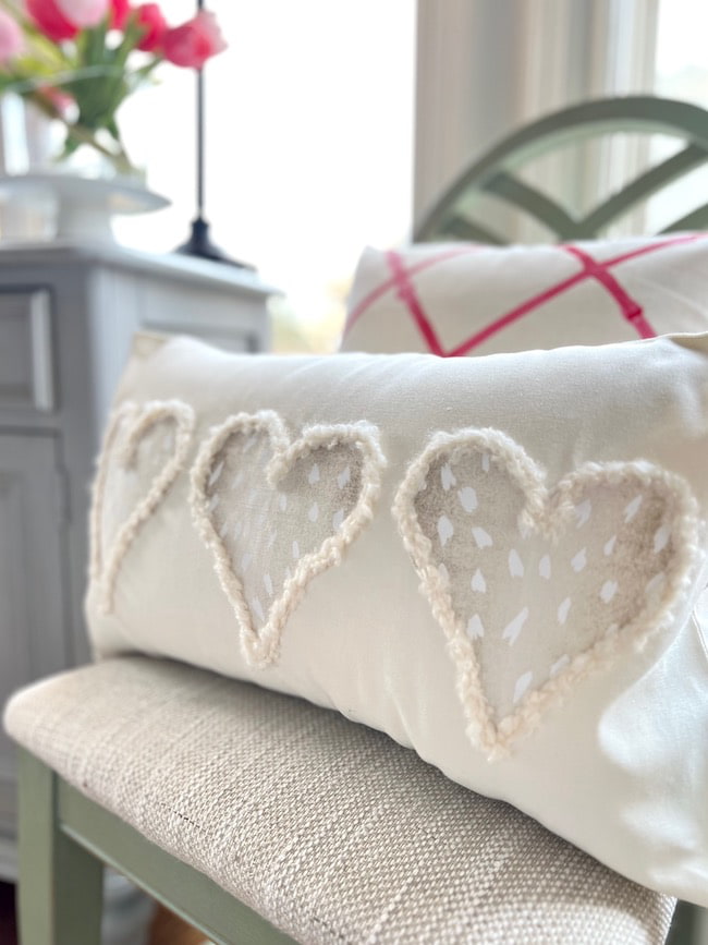 closeup of pillow with three fabric hearts outlined in fuzzy yarn 