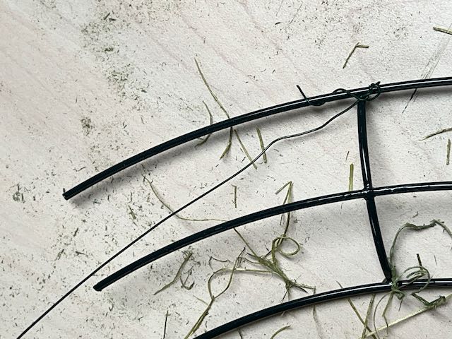 florist wire is twisted around the intersection of frame and rib on the wreath form