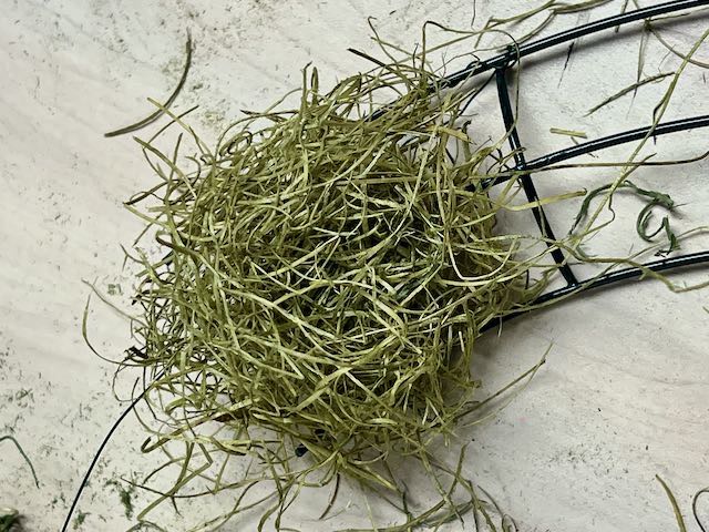 a pile of excelsior grass is covering the three wires of a wreath form