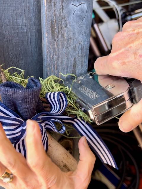 woman's hands are using staple gun to attach the bottom of the wreath to the door