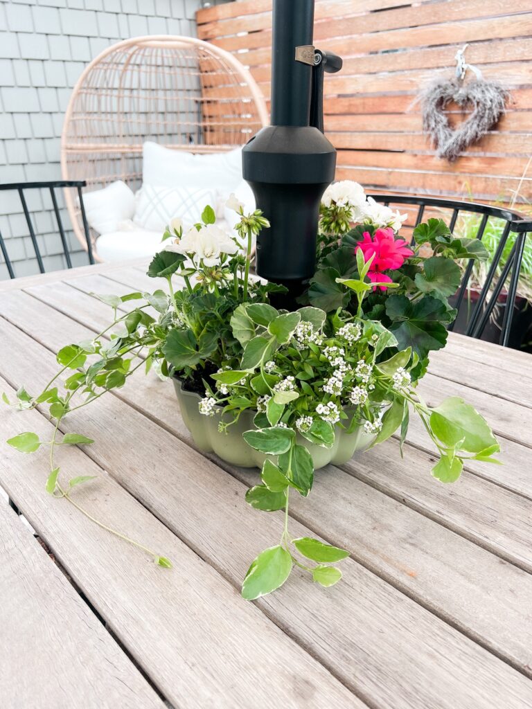 A thrifted bundt pan is shown as a planter around a patio umbrella