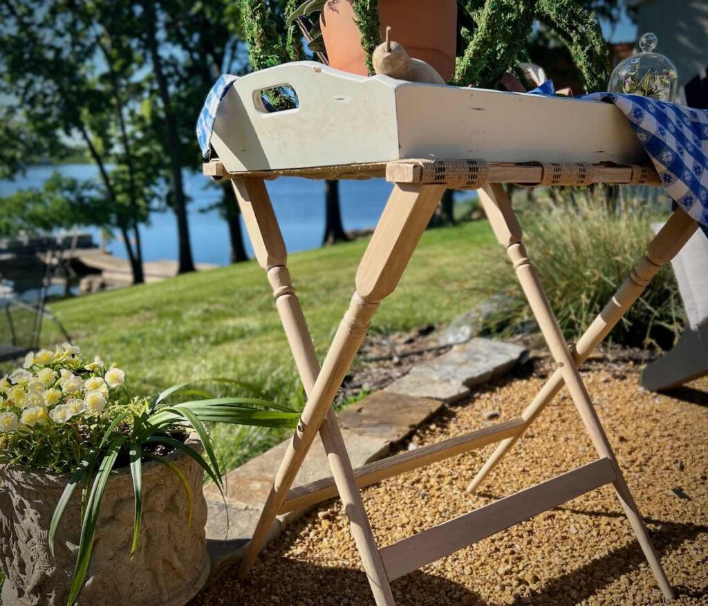 luggage rack is styled on a gravel patio overlooking a lake with a large tray on top with decorative items