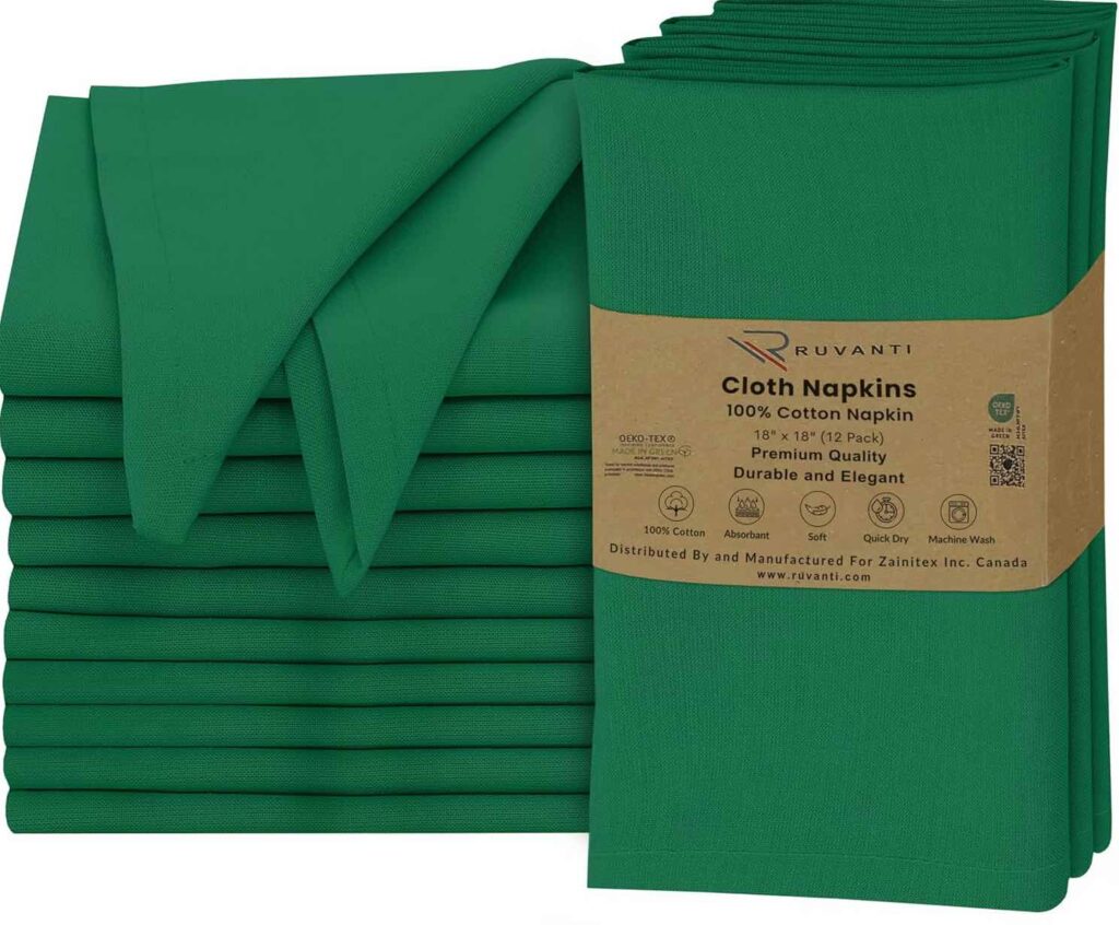 A stack of green cloth napkins next to a neatly folded single napkin could effortlessly transform your table into a festive setting. A brown label reads "Ruvanti Cloth Napkins, 100% Cotton, 18"x18" (12 Pack), Premium Quality." Perfect for DIY Mardi Gras decorations with a touch of elegance.