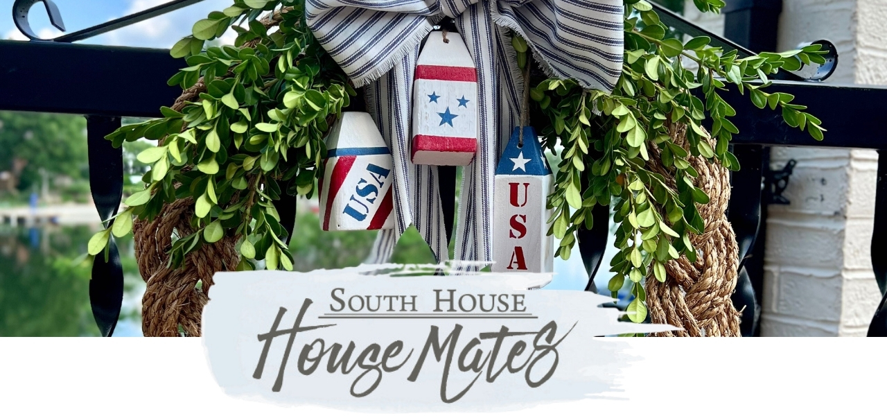 A decorative wreath with greenery, striped ribbon, and red, white, and blue nautical buoys labeled "USA" hangs on a railing. Text below reads "South House House Mates.