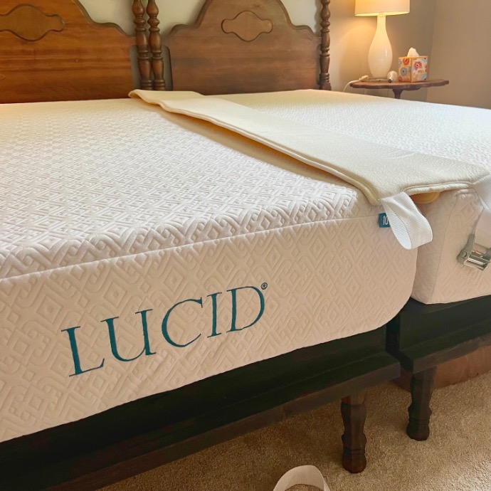 A close-up of two twin beds to X-Long pushed together to form a king bed, each with a Lucid brand mattress and a foam bed bridge in the middle; a lamp and tissue box are visible on a nightstand in the background.