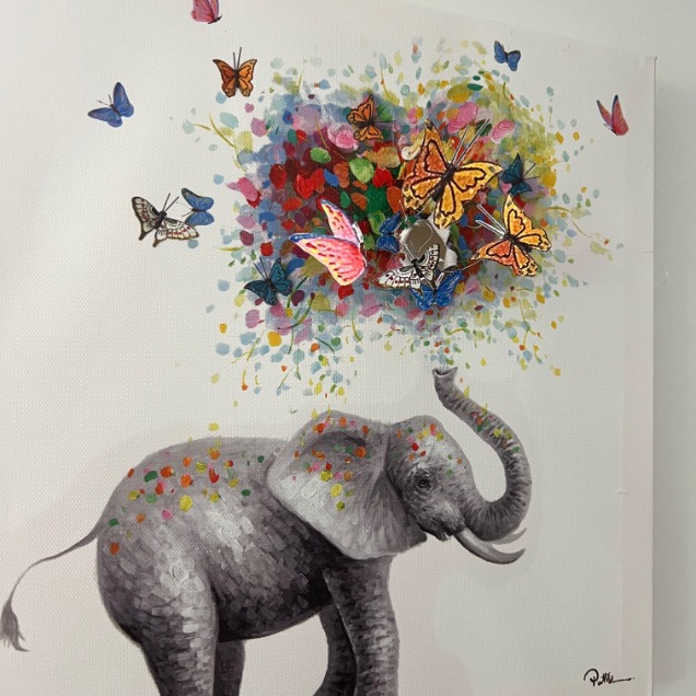 A painting of a gray elephant with colorful spots stands with its trunk raised. From its head bursts a vibrant swirl of butterflies and flowers, creating a lively, imaginative scene against a white background.