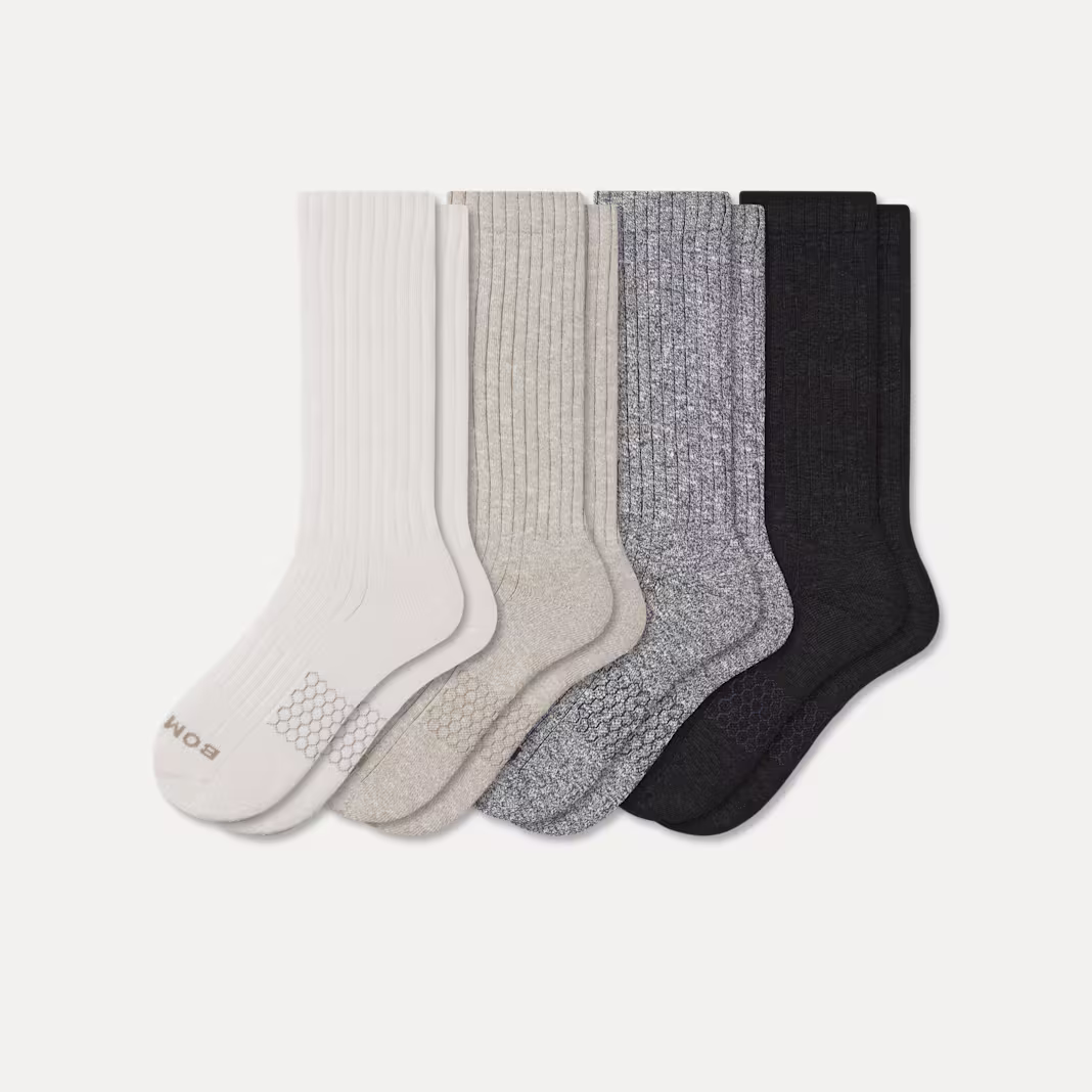 Five pairs of ribbed crew socks in white, light gray, medium gray, dark gray, and black, arranged in a row on a plain background. The white pair has branding on the sole.