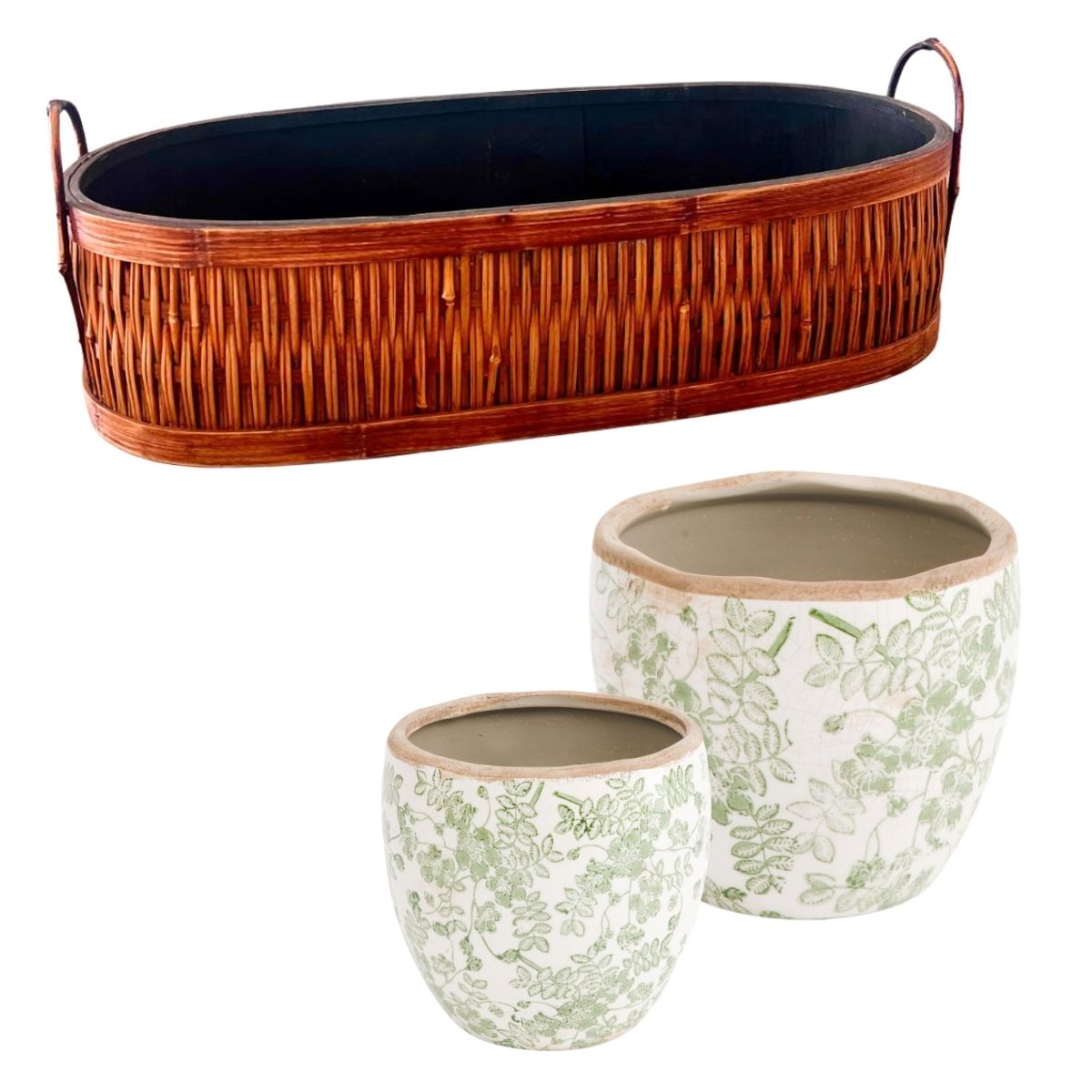 A long, oval wicker basket with handles receives a thrifted basket makeover and pairs beautifully with two round, white ceramic planters decorated with a light green leaf pattern.