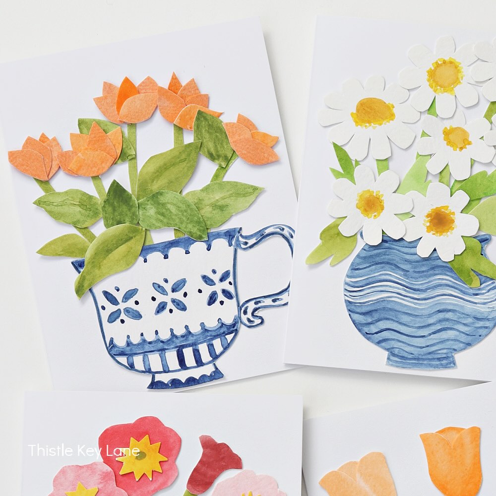 Three greeting cards feature colorful, cut-paper flower bouquets in painted blue and white vases. The flowers include orange tulips, white daisies with yellow centers, and red and pink blossoms.
