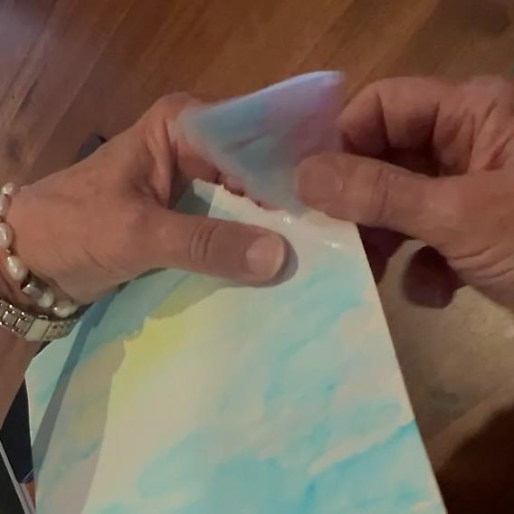A person tears a sheet of watercolor paper along a line drawn with water.