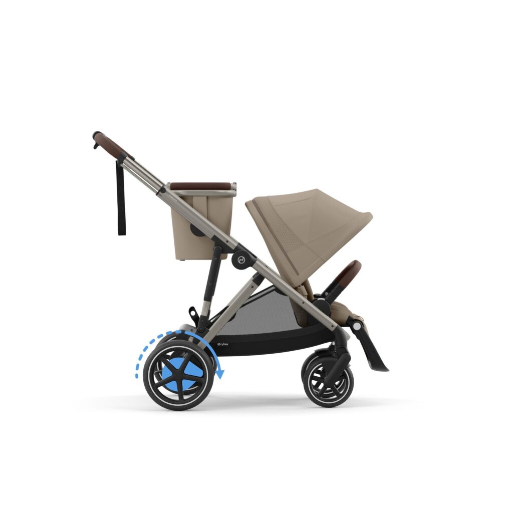 A beige baby stroller with a canopy and brown handlebar is shown in profile. Blue arrows highlight the motion of the rear wheel, indicating it can move or rotate. The stroller has a modern design with a basket underneath.