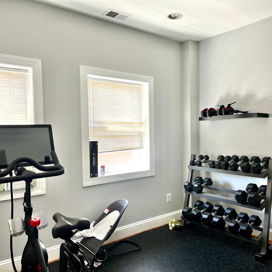 Home gym featuring an exercise bike, a rack of dumbbells, and a wall shelf with additional weights.