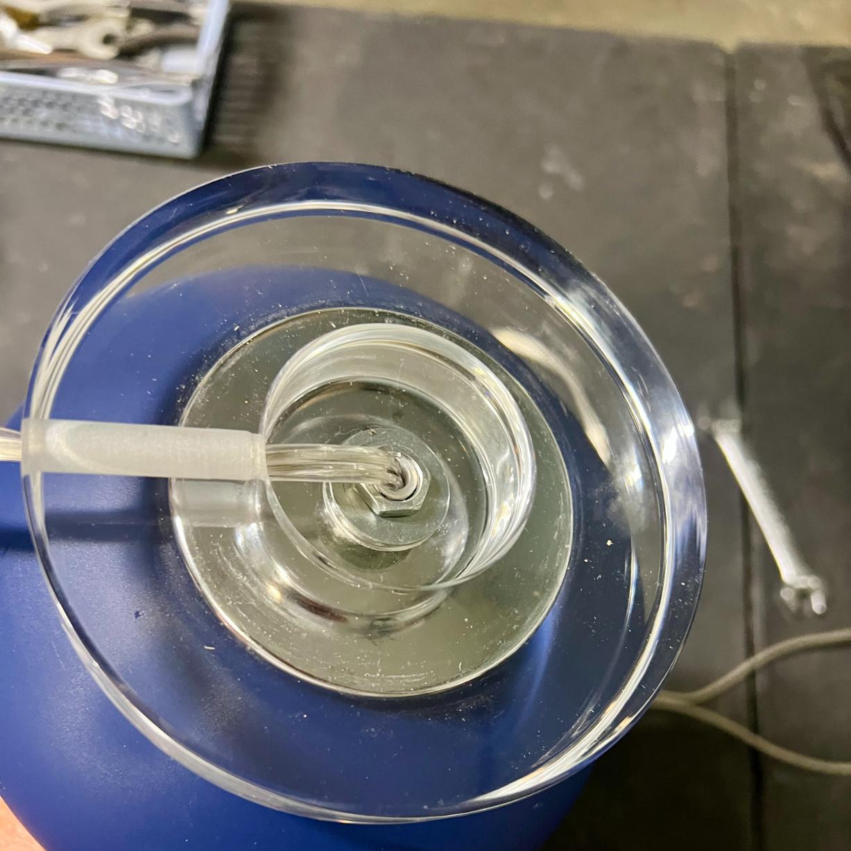 The base of a blue rope wrapped lamp, showing the power cord connection and central metal nut.