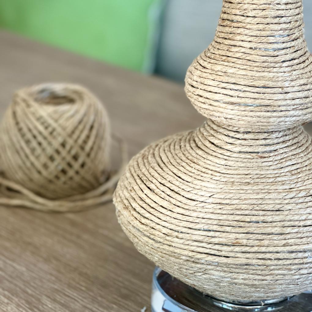 A decorative rope wrapped vase covered in jute twine, with a ball of matching twine sitting in the background.
