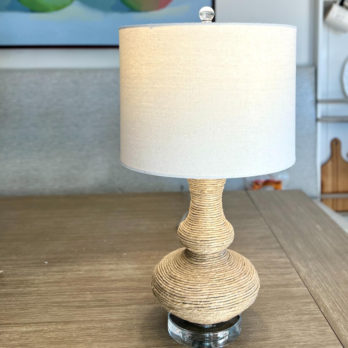 Table lamp with a tiered, rope-wrapped base and a cylindrical off-white fabric shade.